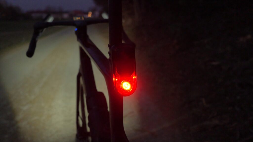Garmin RearVue 820 Radar mit rotem Rücklicht am Fahrrad auf dunklem Weg bei Nacht.