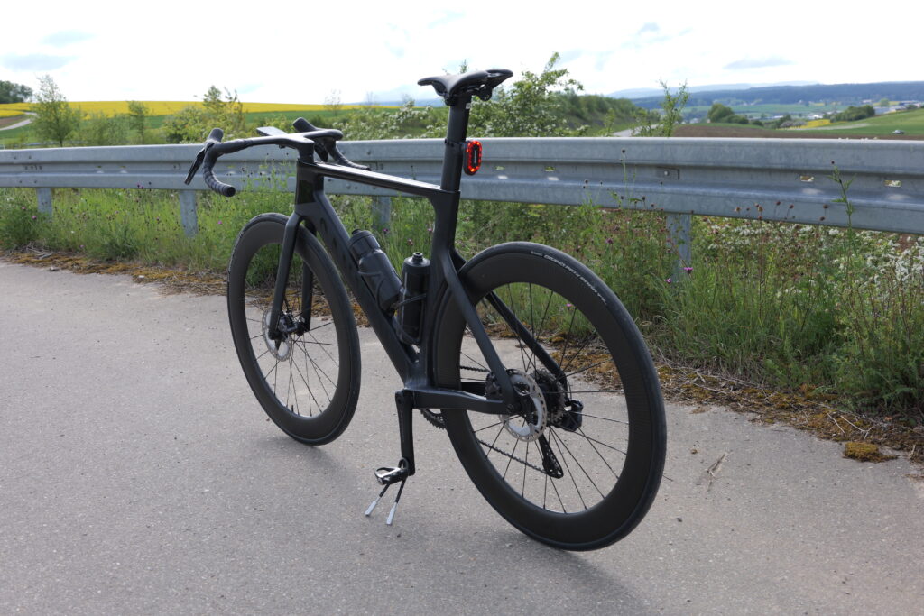 Canyon Aeroad Rennrad mit montiertem iGPSport SR Mini Rücklicht an der Sattelstütze vor Landschaftskulisse.
