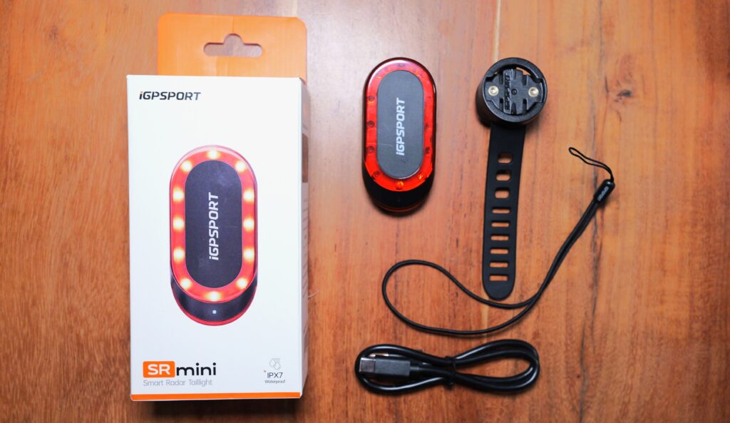 Lieferumfang des iGPSport SR Mini mit Verpackung, Rücklicht, Gummiband-Halterung, Sicherungsband und USB-Ladekabel.