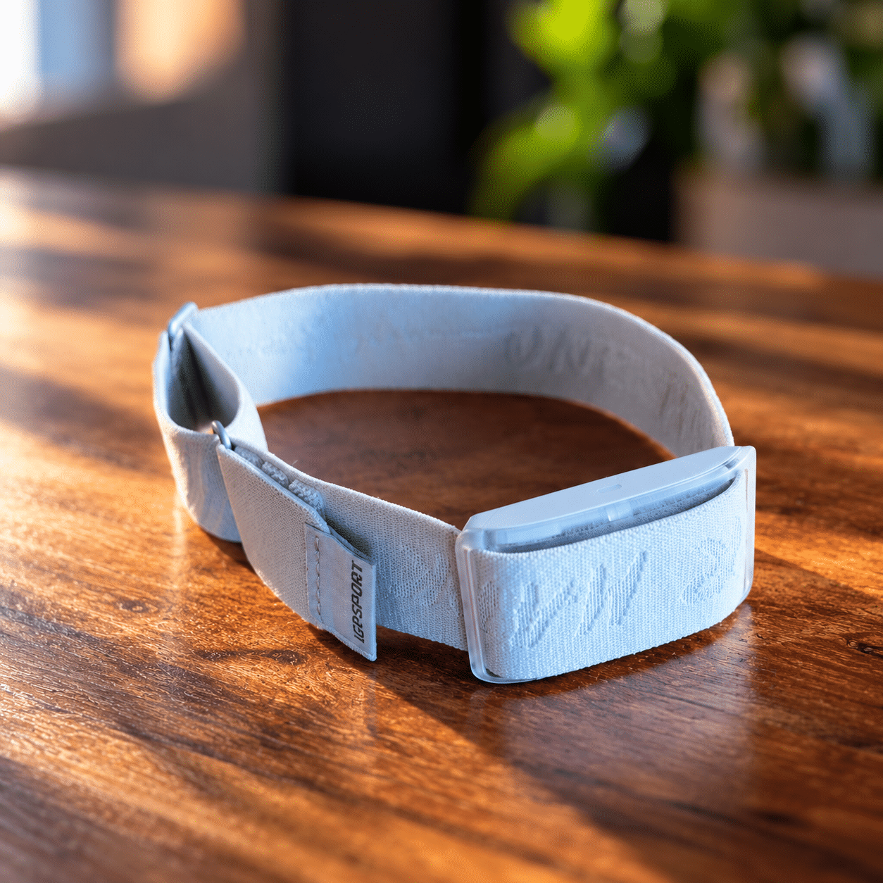 iGPSPORT HR80 Herzfrequenzsensor mit hellblauem Oberarmband auf einem Holztisch
