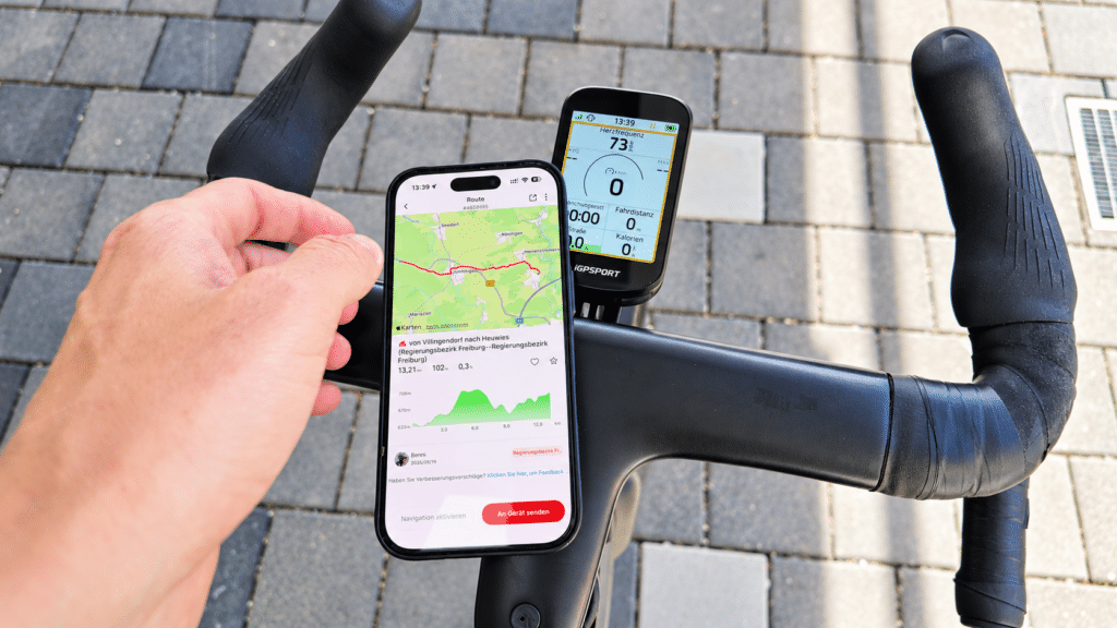 Smartphone mit iGPSPORT-App neben dem BSC200 Pro beim Übertragen einer Route
