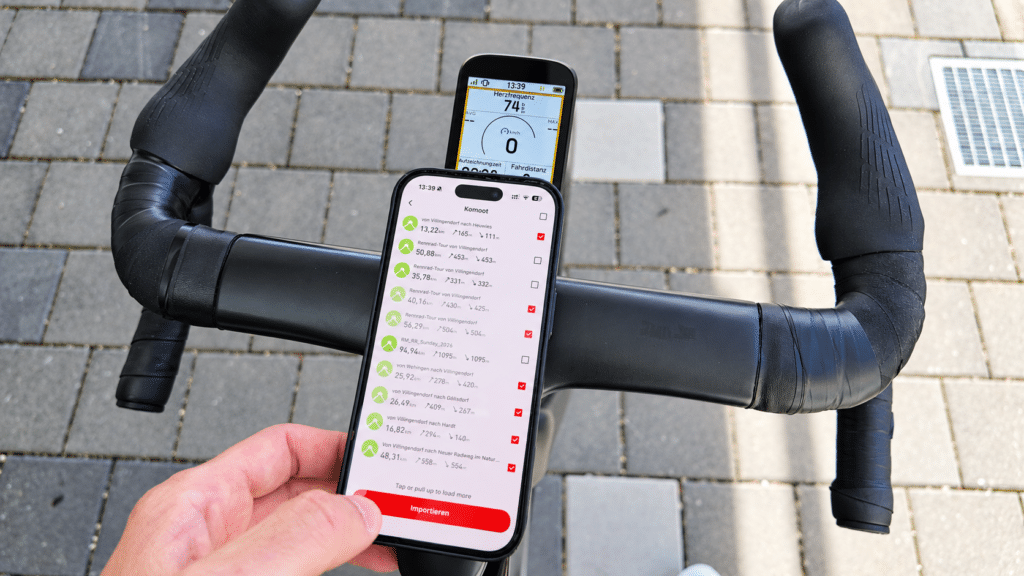 Smartphone mit aus Komoot importierten Routen in der iGPSPORT-App neben dem BSC200 Pro